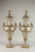A GOOD PAIR OF PORCELAIN VASES AND COVERS with gilt cupids and garlands. 80cms high.