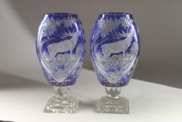 A VERY GOOD PAIR OF BOHEMIAN BLUE TINTED VASES with a panel of a deer, on a square base. 35cms