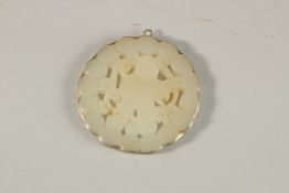 A CHINESE CARVED AND PIERCED CELADON JADE PENDANT. 5cms diameter.