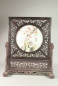 A CHINESE CIRCULAR PORCELAIN PANEL on a wooden stand. 26cms.