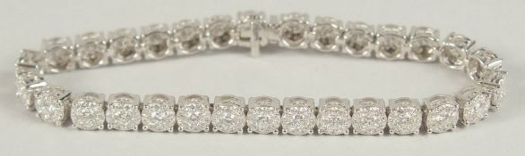 A VERY GOOD 18CT WHITE GOLD AND DIAMOND LINE BRACELET, with thirty illusion set groups of diamonds.
