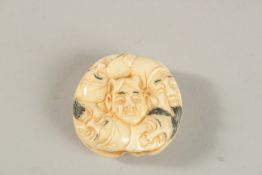 A CARVED BONE NINE-FACES NETSUKE.