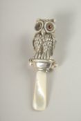 A SILVER AND MOTHER-OF-PEARL OWL RATTLE.