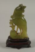 A SMALL CHINESE CARVED JADE COCKEREL AND WOODEN STAND, jade 8.5cm high.