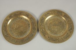 A PAIR OF CHINESE ENGRAVED AND CHASED BRASS DISHES, with central dog of fo, the bases with character