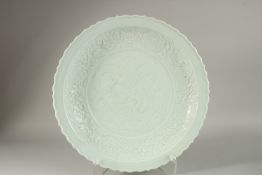 A LARGE CHINESE CELADON GLAZE CARVED DRAGON CHARGER, with petal-form rim, 44cm wide.