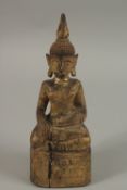 A GILDED CARVED WOOD BUDDHA, with inscriptions to base, 25cm high.