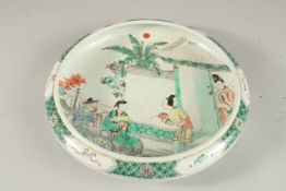 A CHINESE FAMILLE VERTE PORCELAIN DISH, painted with figures in a courtyard, 27cm diameter.