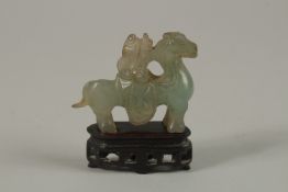 A CHINESE CARVED JADE MINIATURE FIGURE OF A MUSICIAN ON HORSEBACK, with wooden stand, jade 5cm