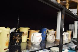 A large quantity of pub jugs advertising Bells and other whiskies etc together with a cow creamer
