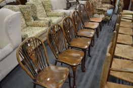 A set of four wheel back dining chairs together with three similar chairs.
