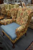 A Georgian style wing armchair on carved cabriole legs with claw and ball feet.