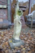 A large reconstituted stone garden ornament modelled as a young lady carrying a pitcher.