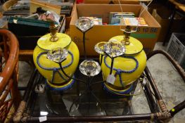 A tea light holder and a pair of yellow pottery table lamps.