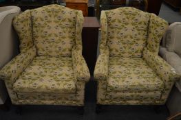 A pair of Georgian style wing armchairs on carved cabriole legs with claw and ball feet.