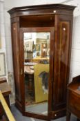 An Edwardian inlaid mahogany corner wardrobe with a single mirrored door.