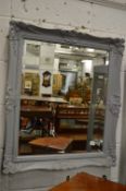 A decorative mirror with grey painted frame.