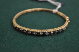 A 9ct gold diamond and sapphire bangle.