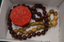 A Chinese cinnabar style box and cover and two decorative bead necklaces.