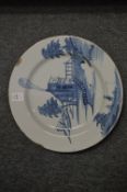 An 18th century tin glazed blue and white charger decorated with building by a bridge with a man
