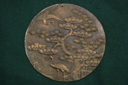 A Japanese circular bronze plaque decorated with cranes and trees.