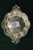 A small shaped silver dish with ribbon work handles.