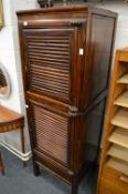 An Eastern stained soft wood two section narrow storage cabinet.
