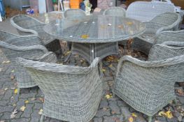 A good large rattan style circular garden table with eight armchairs to include cushions.