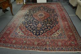 Large Persian style carpet, blue and red ground with stylised floral decoration, some fading,
