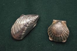 Two silver shell shaped pill boxes.