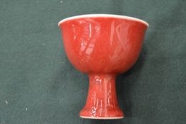 A small Chinese sang de boeuf pedestal cup.