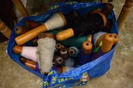 A quantity of large turned wood bobbins with cotton.