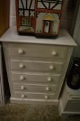 A white painted five drawer chest.