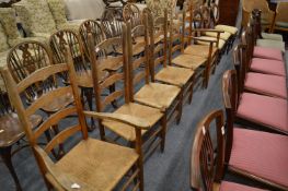 A set of six ladder back and rush seated dining chairs, two with arms.
