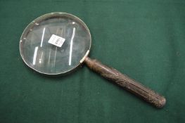 A large magnifying glass with decorative metal handle.