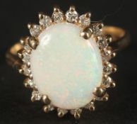 A TRADITIONAL STYLE 14CT YELLOW GOLD CLUSTER RING set with an oval cabochon white opal, surrounded
