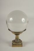 A LARGE CRYSTAL BALL, 4.5ins diameter, on a bronze stand.