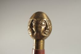 A WOODEN WALKING STICK WITH THREE HEADS HANDLE.