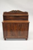 A LATE REGENCY MAHOGANY CHIFFONIER with shaped back, single shelf over a pair of double doors, on