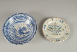 A CONTINENTAL BLUE AND WHITE FAIENCE POTTERY BOWL, decorated with a bird, and a faience dish