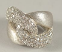 A SILVER AND CZ CROSSOVER RING.