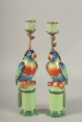 A PAIR OF PORCELAIN PARROT CANDLESTICKS on pedestals. 13ins high.