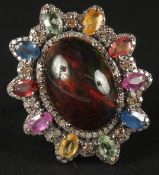 A LARGE DRESS RING set in white metal with cabochon galaxy black opal surrounded by multi coloured