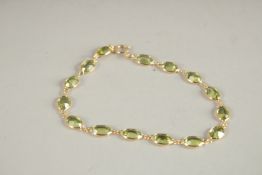 AN 18CT YELLOW GOLD AND PERIDOT BRACELET.