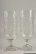 A PAIR OF CUT GLASS STORM LANTERNS on stepped bases. 15.5ins high.