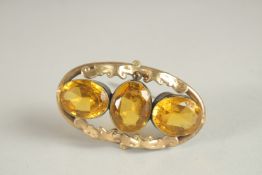 A DECORATIVE BROOCH, set with three citrine coloured stones. 6cms wide.