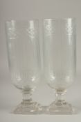 A PAIR OF CUT GLASS STORM LANTERNS on stepped bases. 15.5ins high.