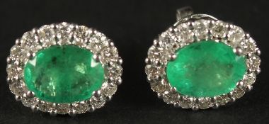 A PAIR OF OVAL EMERALD AND RBC DIAMOND CLUSTER STUDS, boxed. Emeralds 2.08ct. Diamonds 0.73ct.