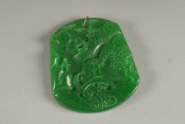 A CARVED APPLE GREEN JADE PENDANT with gold ring.