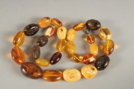 A STRING OF TWENTY-SEVEN AMBER BEADS. 65cms long.